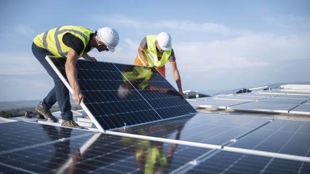 Two workers install a solar panel